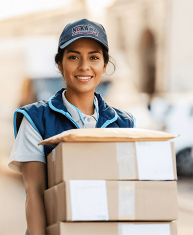 Profesional de NDKA con uniforme sosteniendo cajas de envío, representando la importancia de insumos de calidad en la última milla
